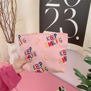 Detailed close-up of pink corduroy makeup bag featuring KEEP SMILING print and soft texture