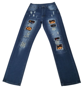 Détail d'un jean bleu foncé usé avec des patchs imprimés de citrouilles pour Halloween