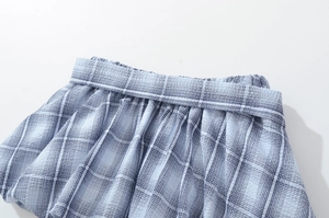 Detail of light blue checkered seersucker skirt with elastic pleated waistband and soft texture