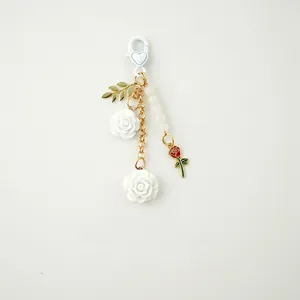 Detail of white resin camellia and enamel rose pendant with heart-shaped lobster clasp