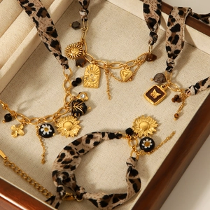 Gold charm bracelets with leopard print fabric and daisy pendants in a wooden tray
