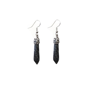 Macro shot of silver ear hooks with black hexagonal crystal pillars and hollow floral caps
