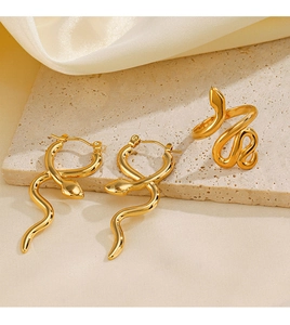 Golden snake jewelry set with earrings and ring displayed on a stone surface
