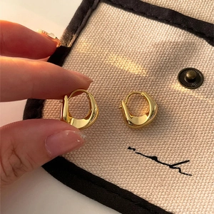 Detailed view of golden irregular curved hoop earrings on beige canvas pouch