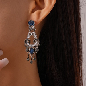 Close-up of vintage tassel earrings with blue oval stones and pearls on a model