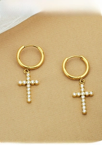 Close-up of gold-plated titanium steel cross earrings with sparkling white zircons