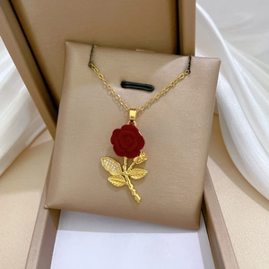 Detailed close-up of a gold rose necklace with red velvet petals and zircon leaves