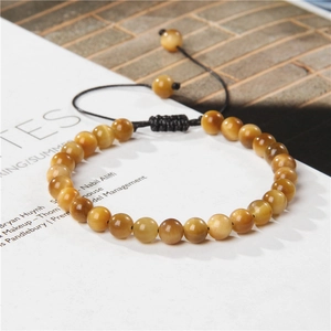 Detail of 6mm tiger eye stone bracelet with adjustable black braided cord on a magazine