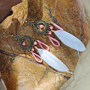 Detailed macro of Bohemian long tassel earrings with pink beads and soft white feathers