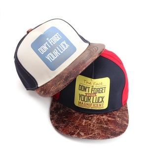 Detail of snapback caps featuring vintage embroidery and faux leather brims in two colors