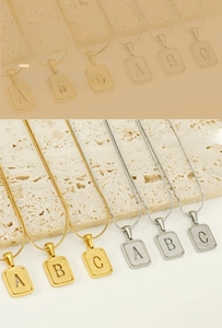 Détail de pendentifs lettres en acier inoxydable or et argent 18K sur chaînes serpent