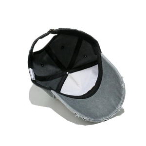 Detail of vintage washed cotton baseball cap showing frayed brim and 100% cotton inner lining
