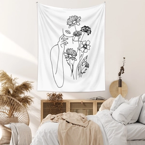 Detailed view of minimalist line art tapestry featuring woman's face and daisies on beige wall