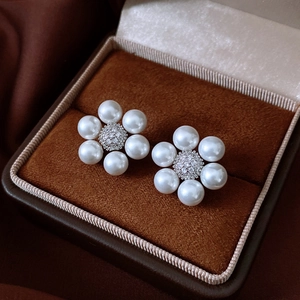 Detail of floral earrings with pearls and cubic zirconia in a brown velvet jewelry box