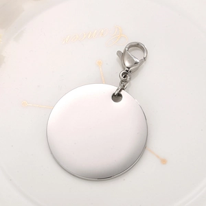 Macro view of a silver circular stainless steel pendant with lobster clasp on a ceramic dish