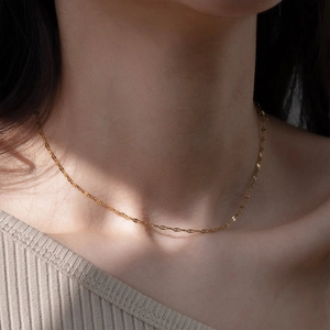 Close-up of a minimalist gold layered necklace on neck showing PVD plating texture