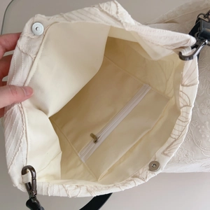 Beige cotton tote with floral embroidery, interior zipper pocket, and magnetic closure