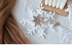 White glitter snowflake and reindeer ornaments arranged with a candle on a wooden tray