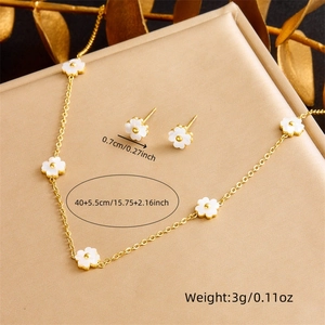 Floral white shell necklace and earring jewelry set with golden chain on dark background