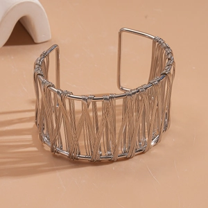 Detail view of woven hollow silver wide cuff bracelet on a minimalist display
