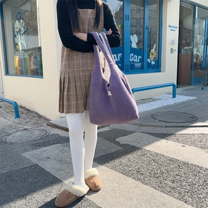 Close-up of a purple faux fur reversible tote bag in a casual street style setting