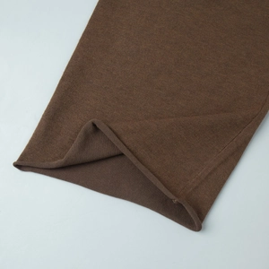Détail du tissu en maille marron montrant la texture et le bord roulé naturel