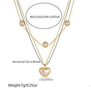 Detail of layered gold stainless steel necklace with round and heart pearl pendants