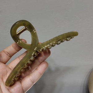 Detailed view of a large translucent olive green hair claw clip with a strong metal spring