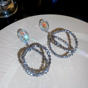 Détail de boucles d'oreilles de luxe avec cristaux et opales sur une assiette blanche