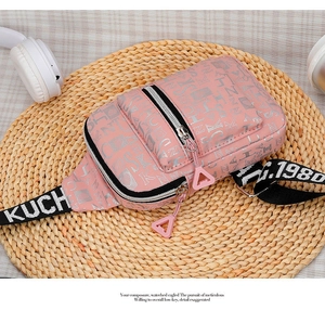 Detail of pink crossbody chest bag featuring silver letter print and woven strap