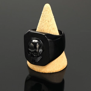 Macro detail of vintage black stainless steel skull ring on a wooden cone display stand
