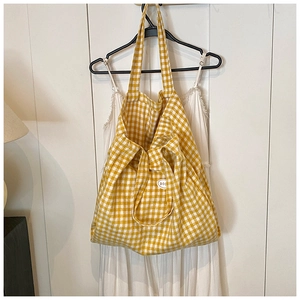 Detail shot of yellow plaid canvas tote bag showing textured fabric and brand logo