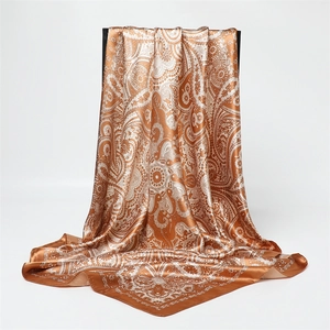Détail d'un foulard en satin de soie orange à motif paisley avec un drapé élégant