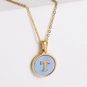 Macro detail of 18k gold plated necklace with blue shell inlay and golden T letter