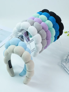 Close-up of sponge headbands in various colors on acrylic stand showing handmade tags