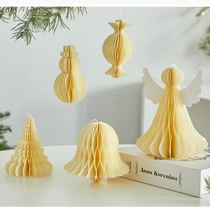 Detail of five beige honeycomb paper ornaments hanging on pine branches for Christmas decor