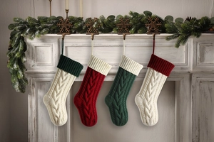 Close-up of four cable knit Christmas stockings hanging on a festive decorated mantel