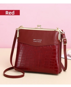 Detail of red crocodile pattern leather crossbody bag with vintage gold kiss-lock closure