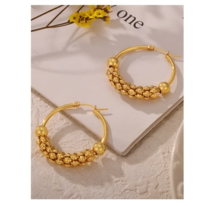 Detailed view of gold-plated U-shaped earrings with textured micro-bead patterns