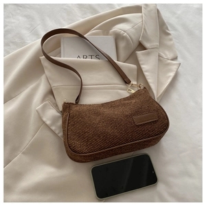 Flat lay of vintage dark brown corduroy underarm bag with zipper on a beige blazer