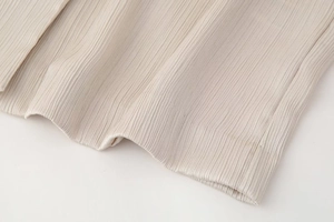 Detailaufnahme der beigen Plissee-Stoffstruktur mit elegantem Fall für Damen-Blazer