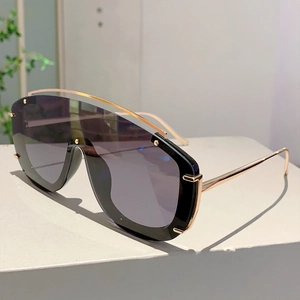 Detail view of avant-garde black shield sunglasses with gold metal frame on display stand