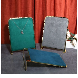 Detail of velvet necklace stands with gold metal frames in green, gray, and peacock blue