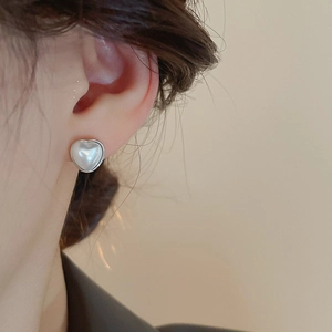 Gros plan de boucles d'oreilles cœur en perles portées sur l'oreille, base argent