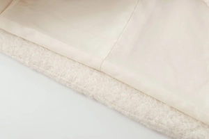 Detailed close-up of double-breasted wool coat showing plush texture and premium stitching