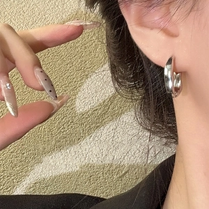 Minimalist thick silver geometric hoop earrings with polished metallic finish on model