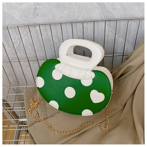 Detail of mushroom-shaped green crossbody bag with white polka dots and gold chain