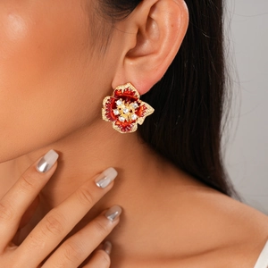 Close-up of red enamel flower earrings with sparkling crystals on a model's ear