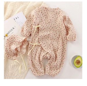 Close-up of baby girl floral romper with tie-front detail and matching cotton sun hat