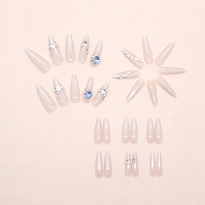 Detalle de uñas postizas stiletto con pedrería azul y efecto de purpurina ojo de gato